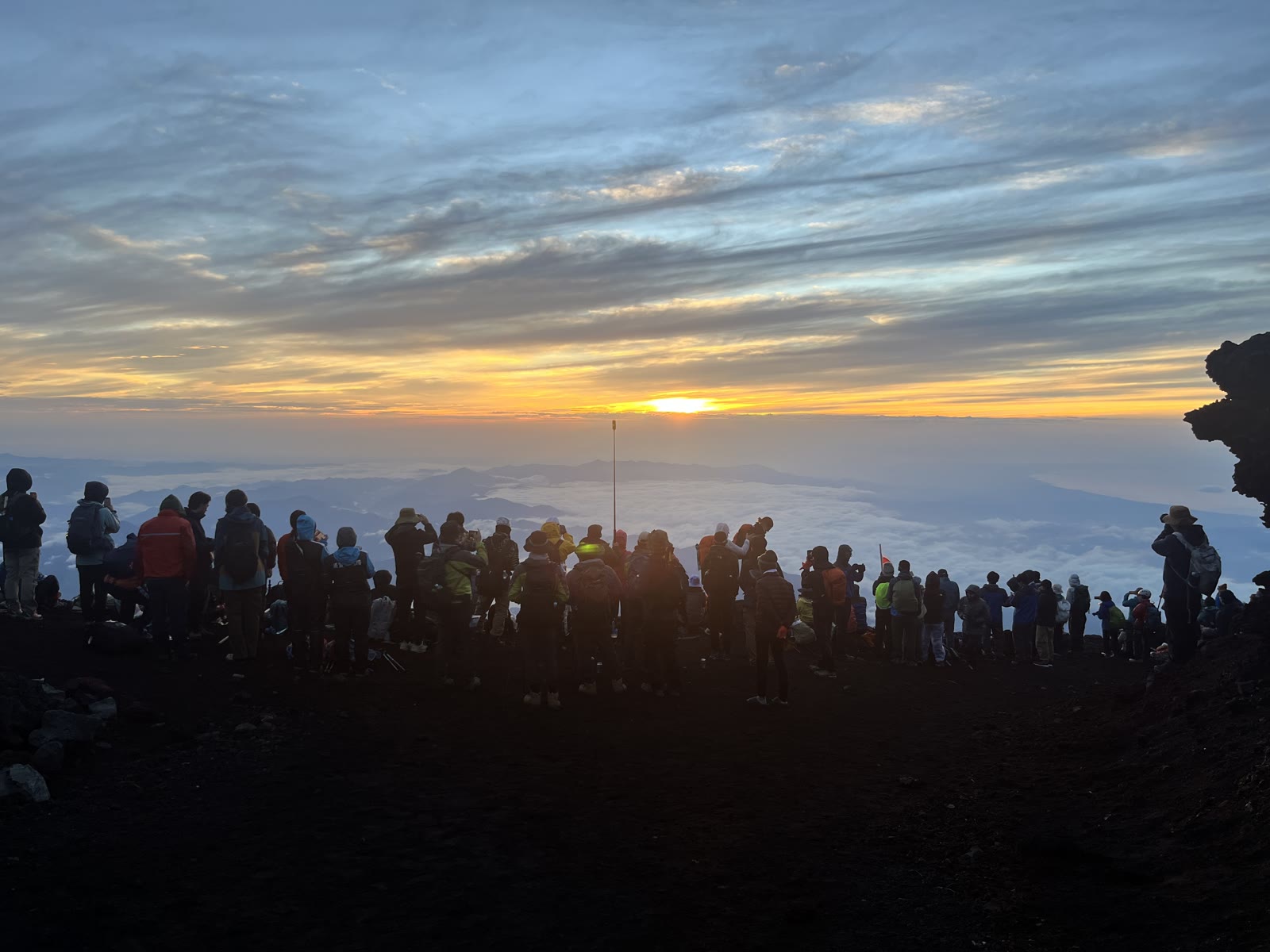 富士山頂から見た雲海とご来光を待つ登山者