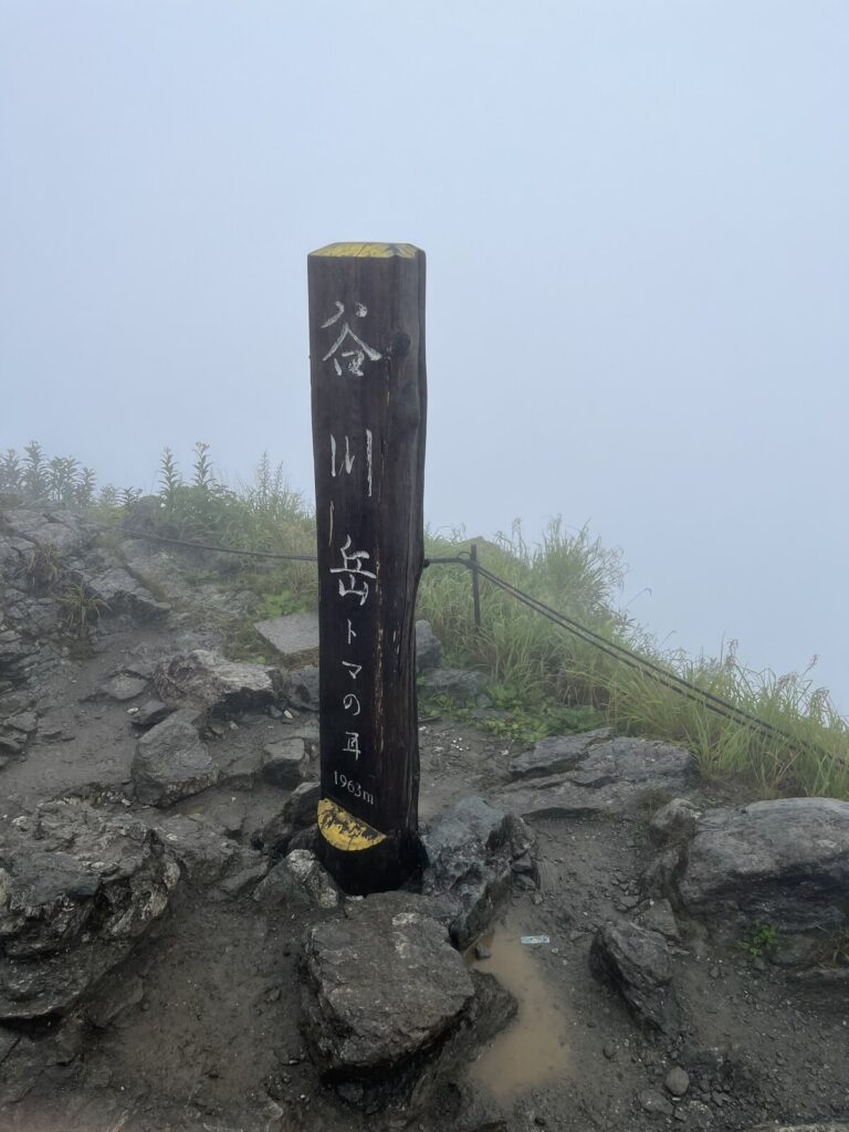 雨と霧の谷川岳トマの耳の山頂標識