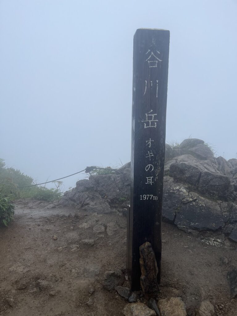 雨と霧の谷川岳オキの耳の山頂標識